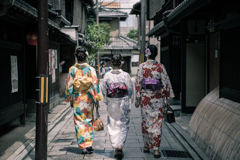 Trois femmes en kimonos colorés marchant dans une rue traditionnelle à Kyoto, Japon