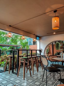 Cozy Bengaluru cafe with stylish wooden stools and lush green plants creating a warm ambiance.