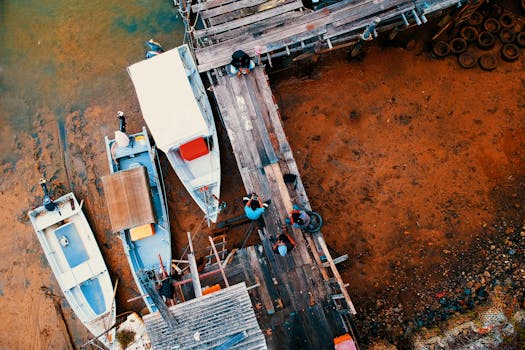 退潮时，航拍镜头捕捉到一个木制码头和船只，其鲜艳的色彩突显了大地色调的活力