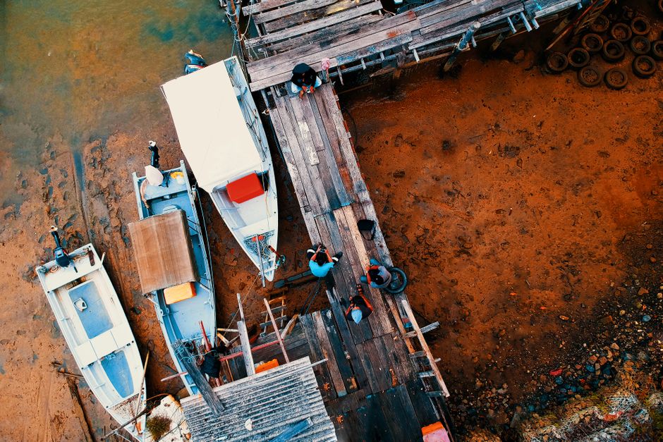 Colorful aerial shot of a wooden dock and boats at low tide, highlighting vibrant earth tones.