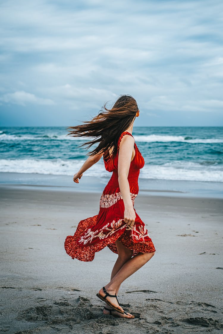 Woman In Red Dress Walking On Beach