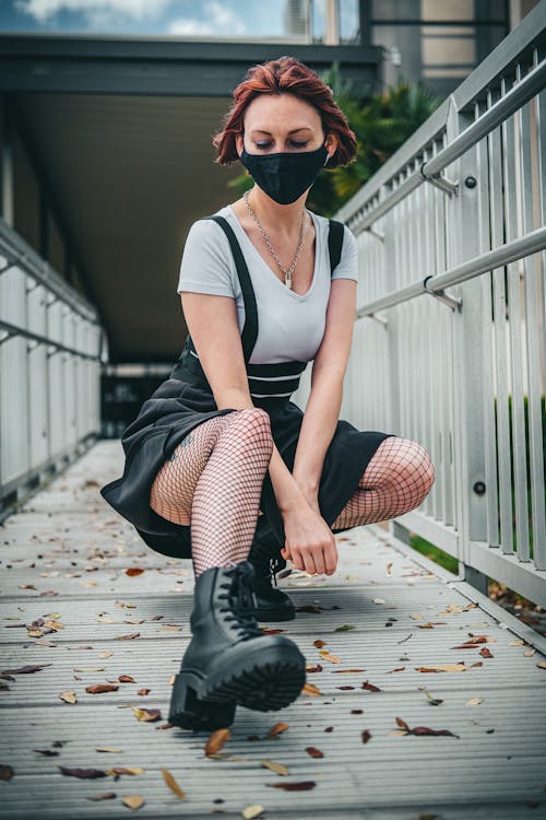 A Woman Wearing Black Face Mask Posing on the Bridge