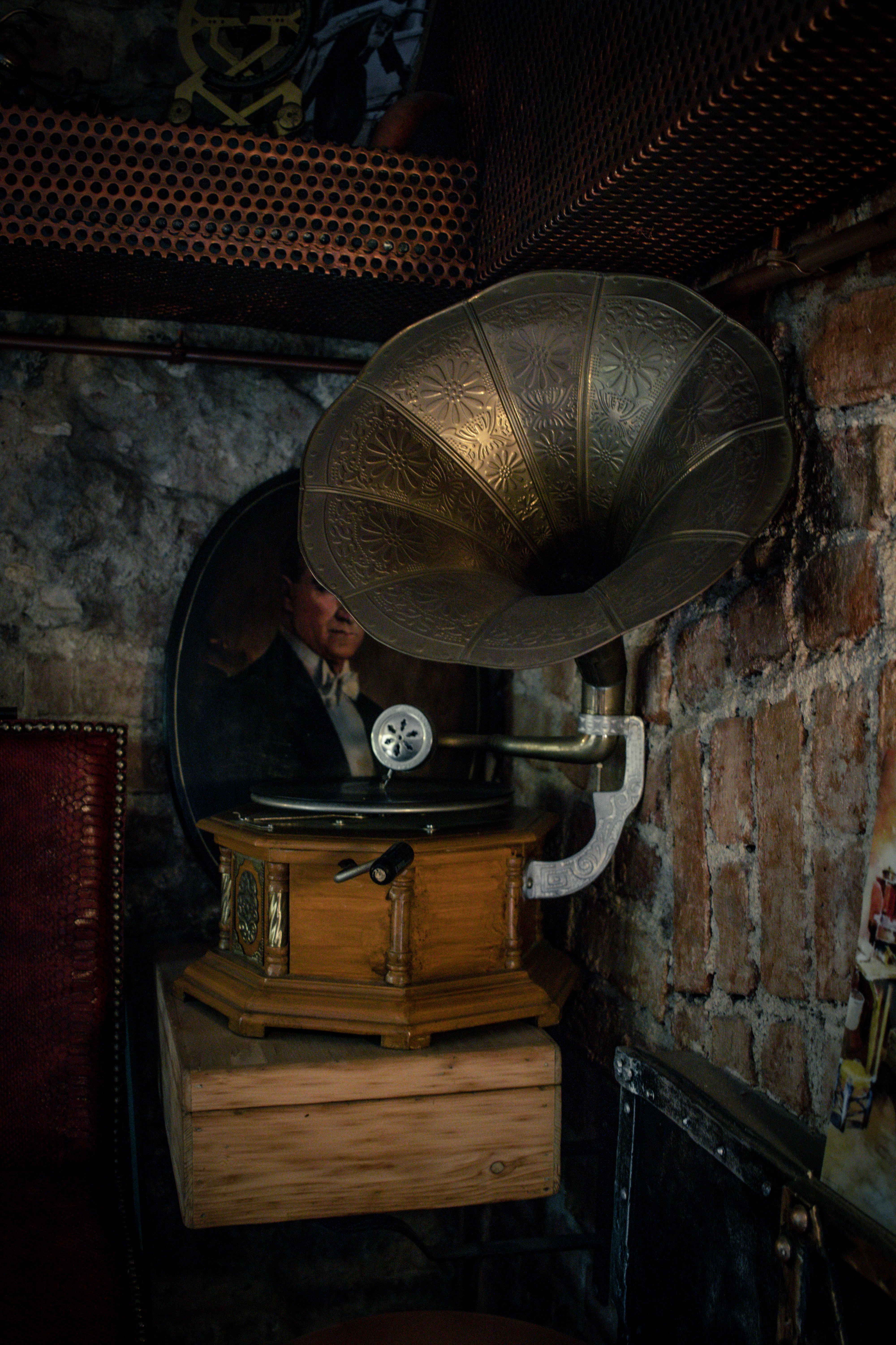 Fotomural Un gramófono antiguo en un ambiente rústico con un espejo que refleja a un hombre con traje vintage.