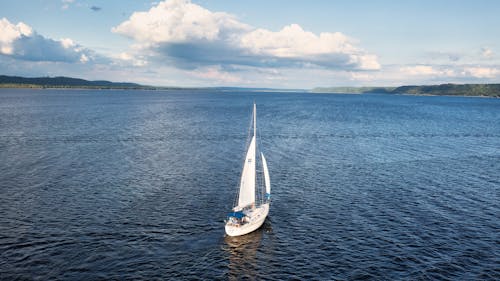 White Sail Boat on Sea Under White Clouds and Blue Sky