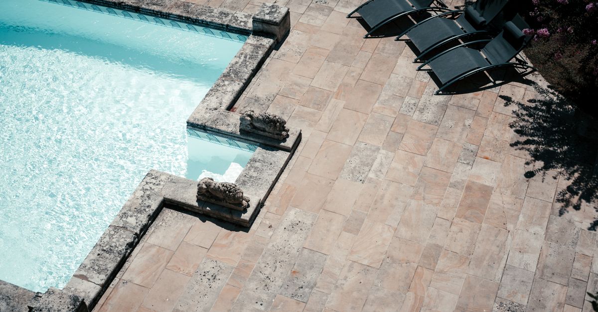 A luxurious top view of a poolside terrace in Bordeaux, featuring sun loungers and tiled flooring.