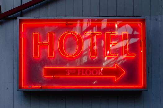 Close-up of a neon hotel sign indicating the 3rd floor, vibrant in red.