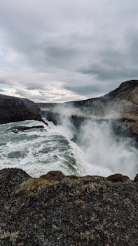 Stunning vertical shot of Gullfoss waterfall in Iceland's rugged landscape.