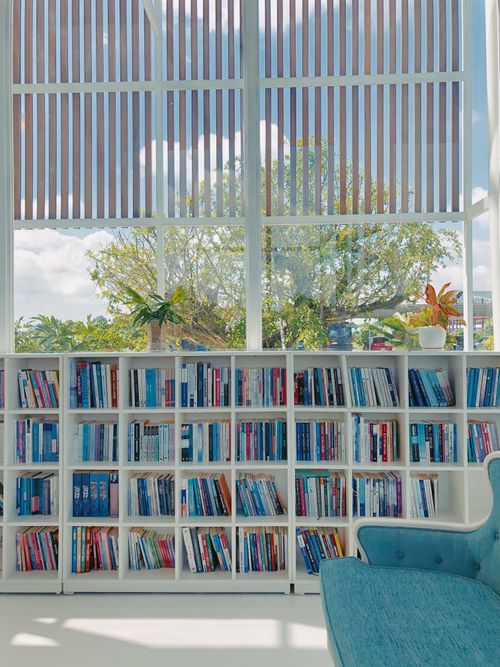 Free Sunny library with bookshelves and a window view of nature. Stock Photo