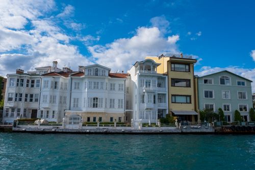 Free Scenic view of elegant waterfront homes facing the sea under a clear blue sky. Stock Photo