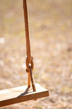 Rustic swing close-up with blurred background, warm tones, ideal for nature themes.