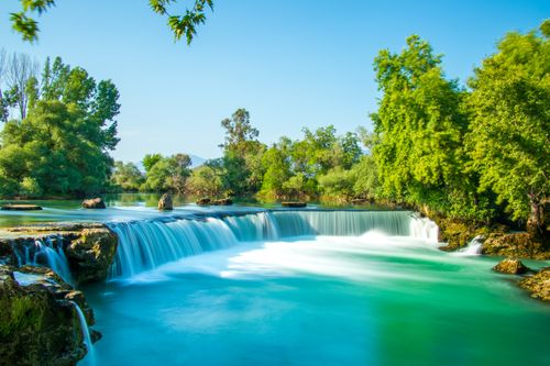 Free Beautiful view of Manavgat Waterfall surrounded by lush greenery on a sunny day Stock Photo
