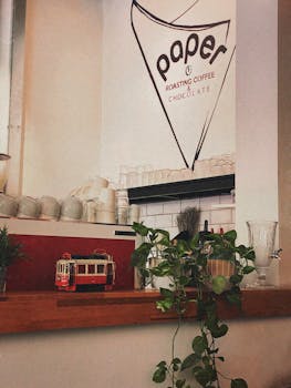 Warm coffee shop interior in Ankara featuring vintage tram model and lush plants.