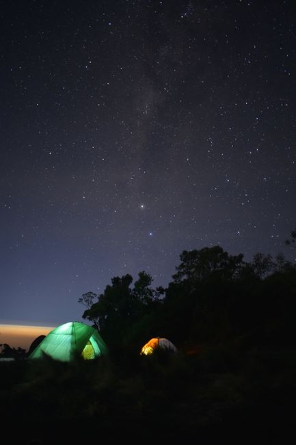 Outdoor camping with glowing tents under a magnificent starry sky.
