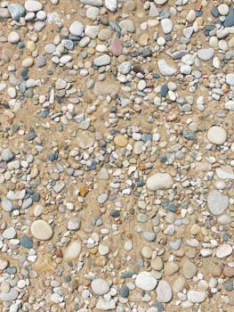 A detailed view of smooth pebbles scattered on a sandy surface, offering a natural texture.