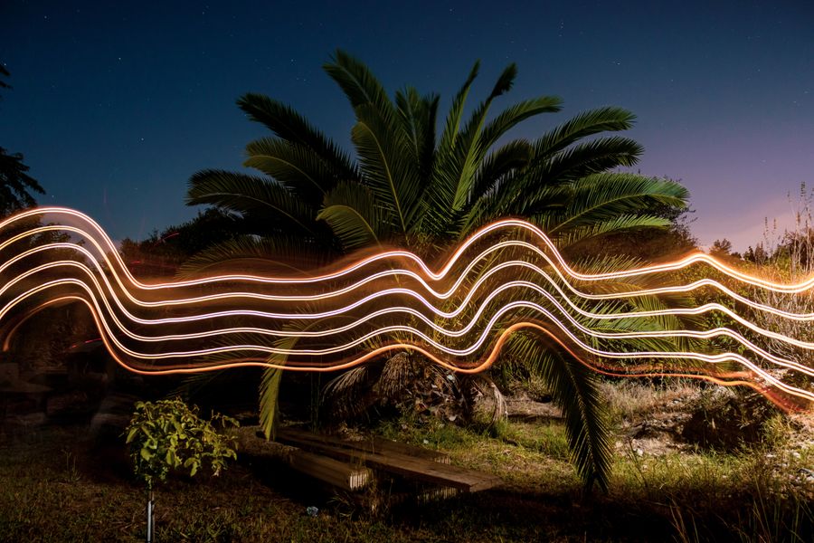 Light trails traced across a dark landscape at night, by Kostas Dimopoulos on Pexels