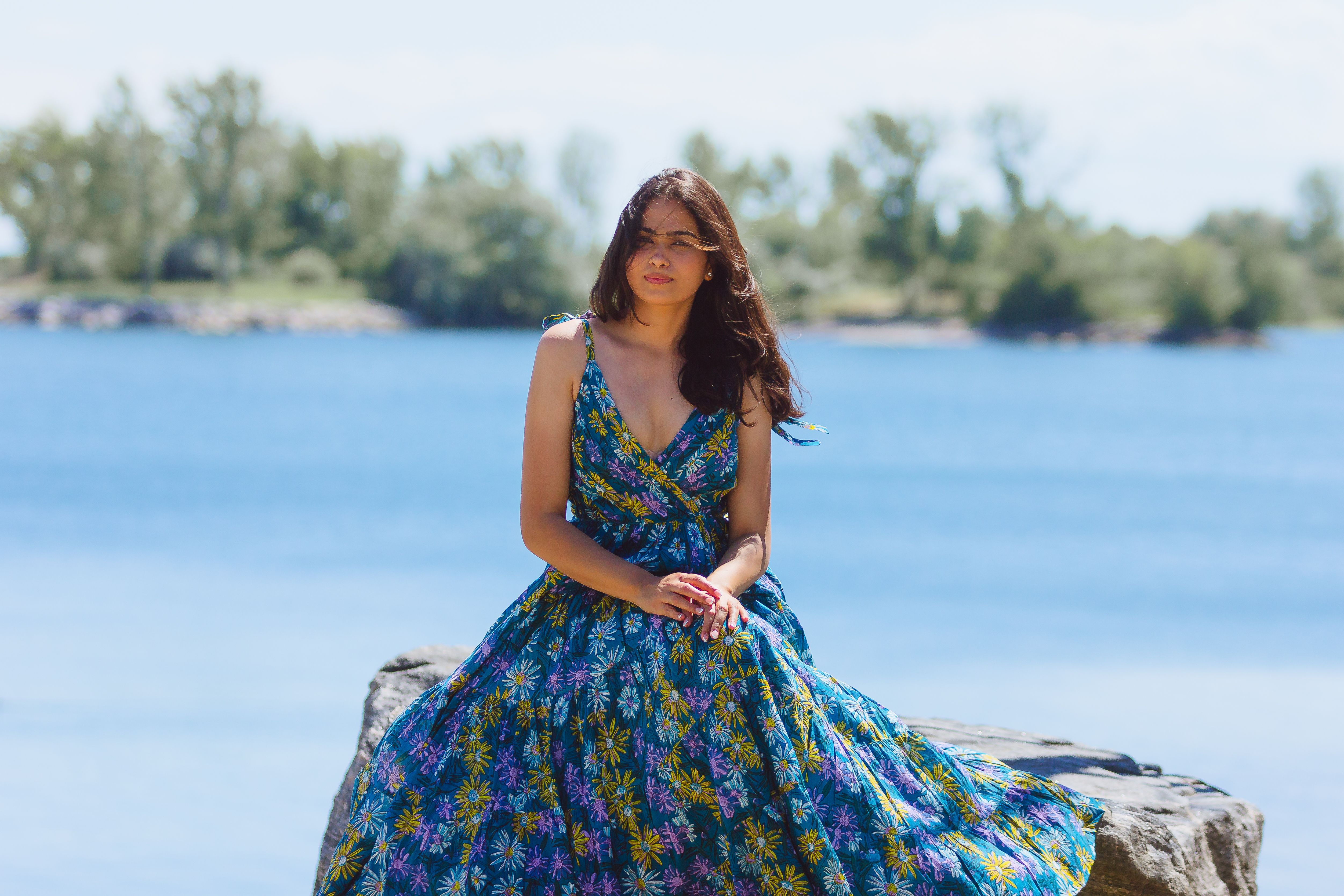 Woman in Blue and White Floral Sleeveless Dress Sitting on Gray Rock ...