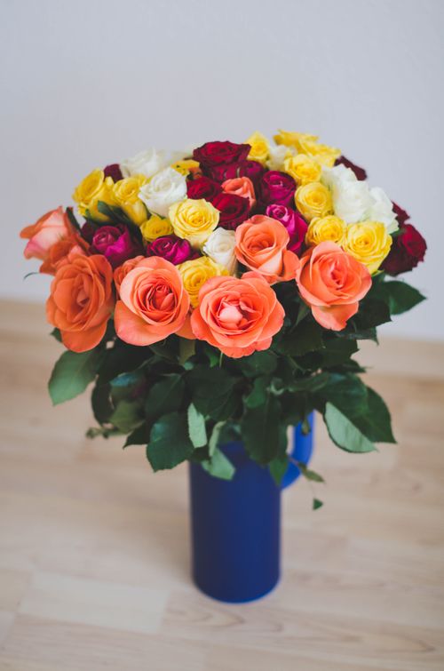 Free A stunning bouquet of multicolored roses in a blue vase, perfect for home decor or floral arrangements. Stock Photo