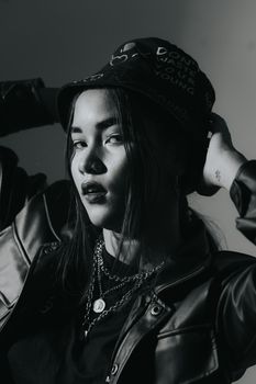 Artistic black and white portrait of a young woman wearing a stylish black hat and leather jacket.