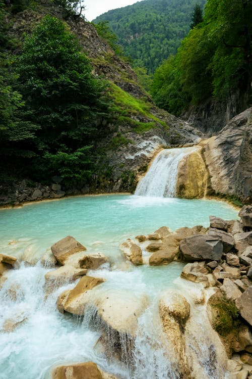 Flowing Waterfall Behind Green Mountains