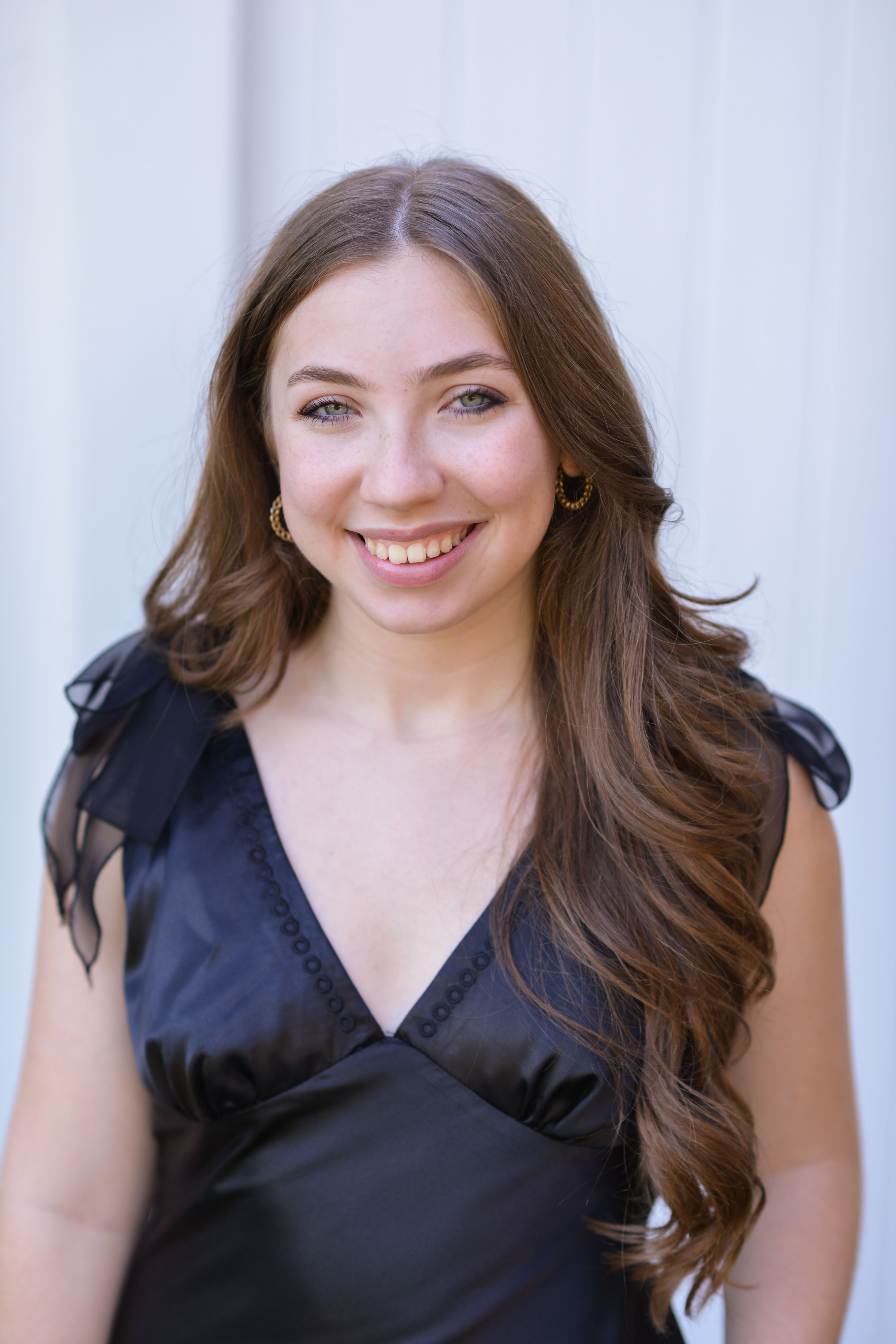 Portrait of a smiling woman wearing an elegant black dress, exuding glamour and confidence.