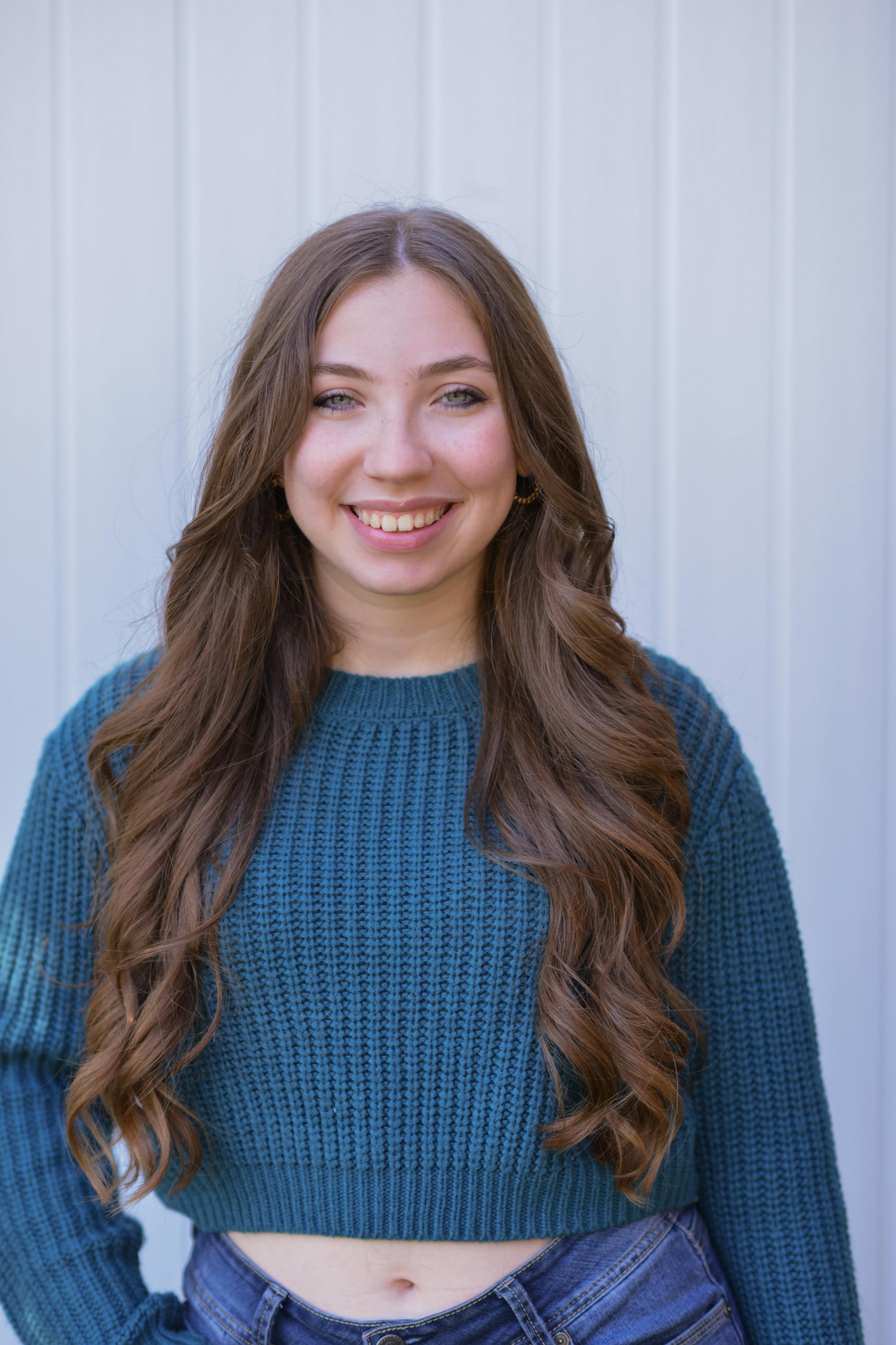 Portrait of a smiling woman in a blue knitted sweater, exuding joy and warmth.
