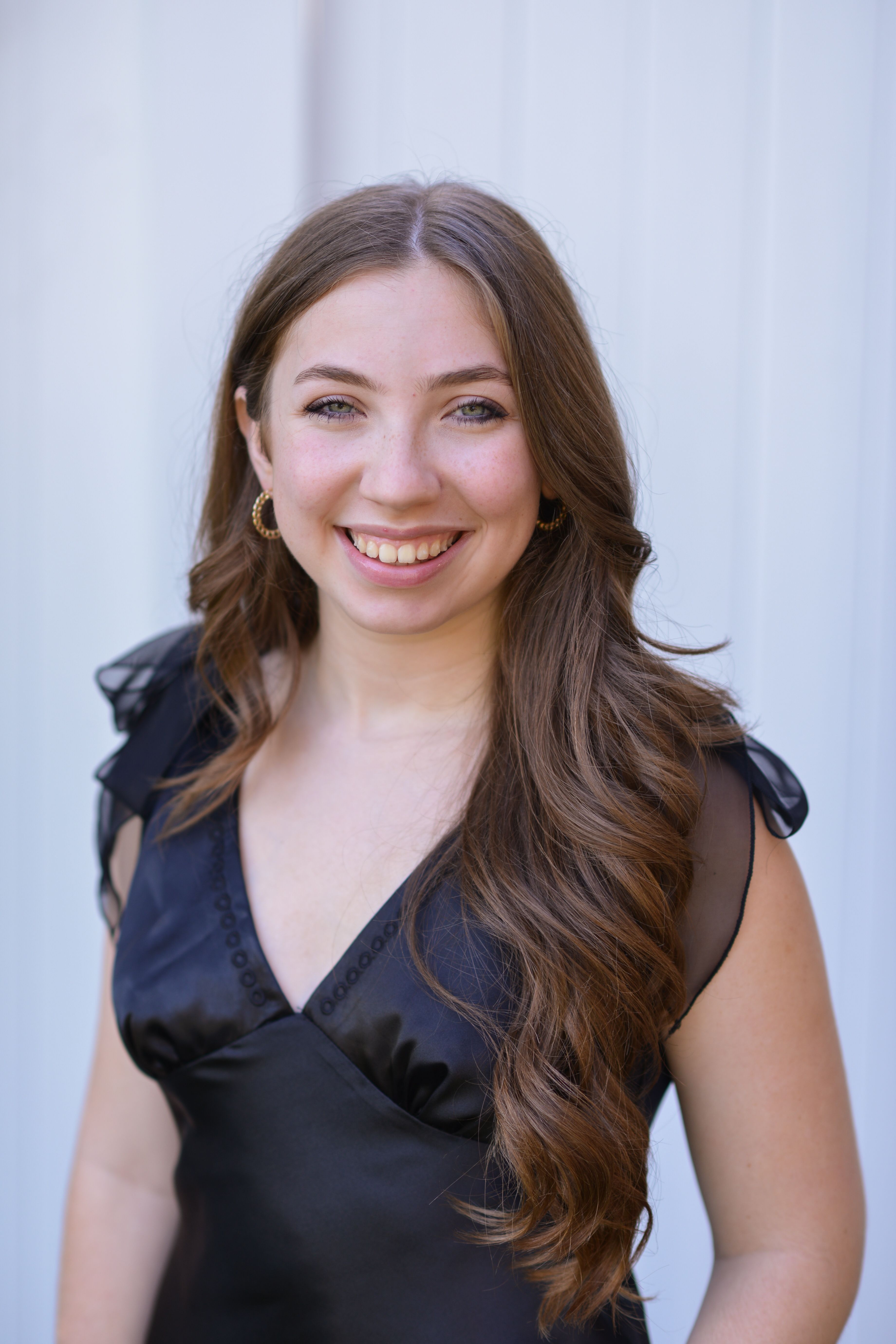 Portrait of a smiling young woman in a black satin dress, creating a warm and inviting atmosphere.