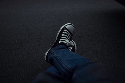 A Person Wearing Denim Jeans and Black and White Sneakers