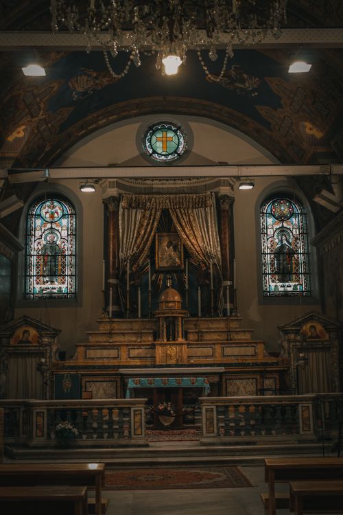 Free Beautifully detailed church interior featuring stained glass windows and an ornate altar. Stock Photo