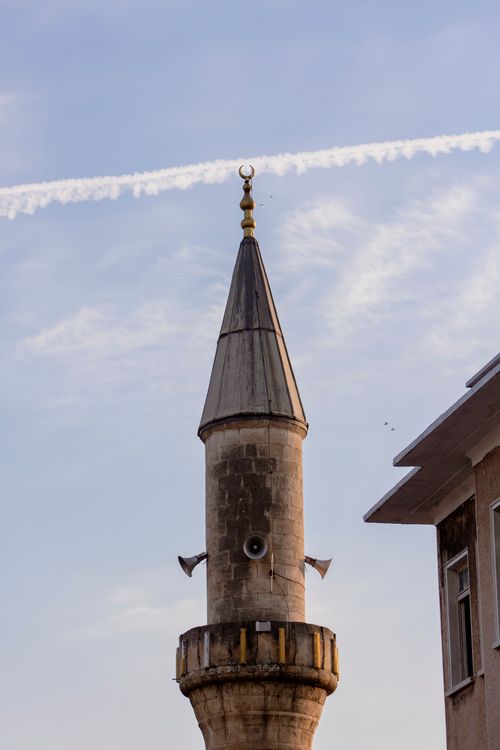 Free A traditional minaret in Adana, Turkey with clear sky and passing contrail. Stock Photo