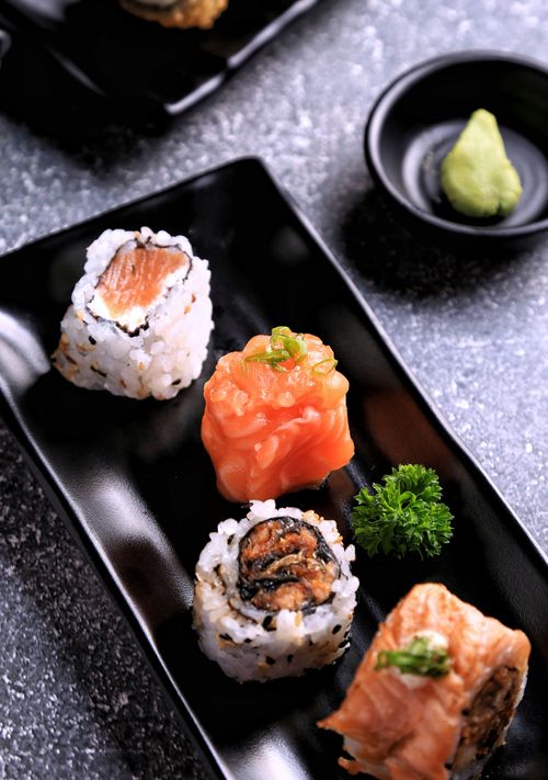 Free Close-up image of diverse sushi rolls with garnish on a black plate. Stock Photo