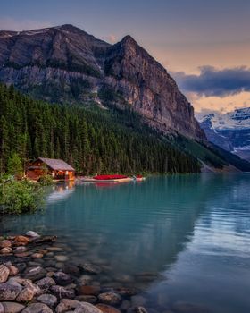 Stunning landscape of Lake Louise, featuring mountains and water reflections at twilight.