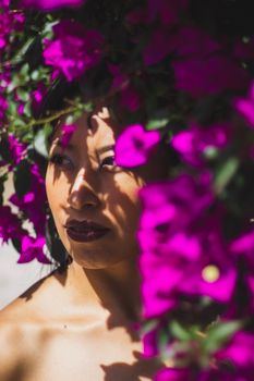 Close-up of a woman partially obscured by vibrant pink bougainvillea flowers.