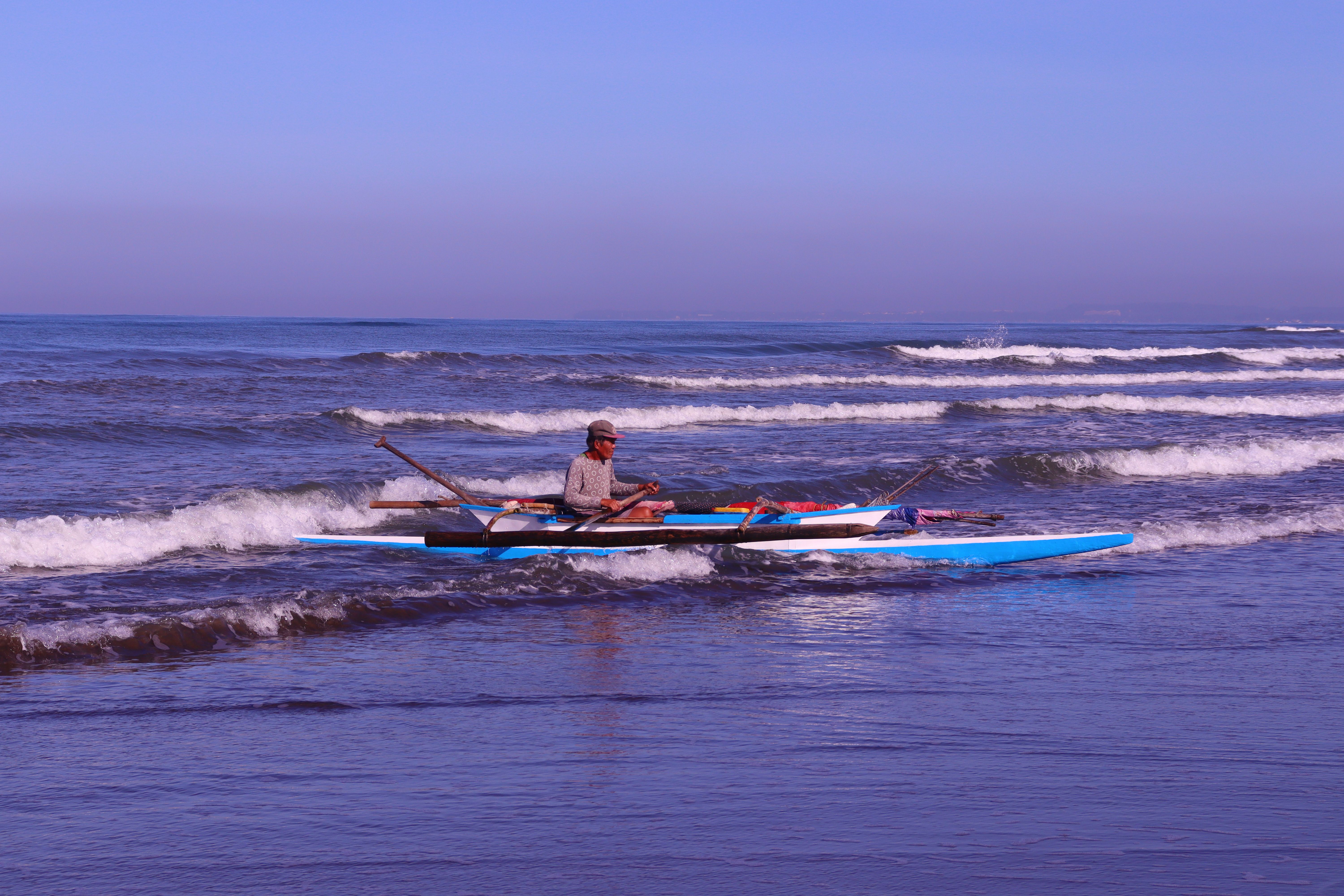 Man Riding on Blue Rowboat on Sea · Free Stock Photo
