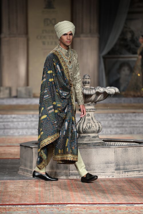 Free Male model wearing traditional Indian sherwani walking on a fashion runway. Stock Photo