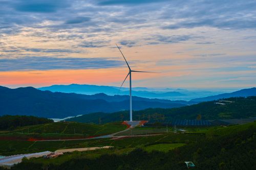 Free A wind turbine stands tall amidst the rolling hills and vibrant colors of sunrise in Da Lat, Vietnam. Stock Photo
