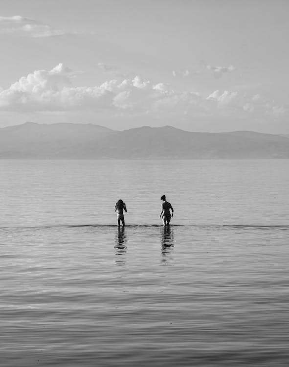 Free Grayscale Photo of a Women Standing on Sea Water Stock Photo