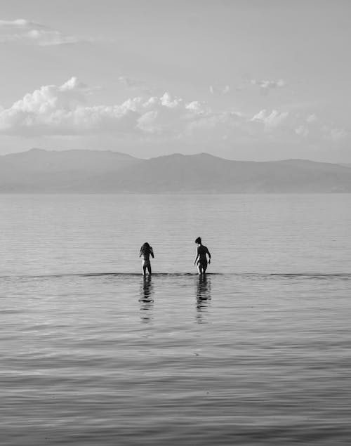 Free Grayscale Photo of a Women Standing on Sea Water Stock Photo