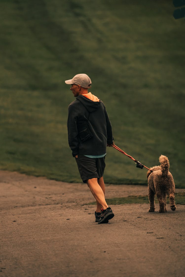 Man In Black Jacket Walking With A Dog