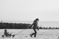 一位母亲拉着坐在雪橇上的孩子穿过雪地，捕捉到了快乐的冬日瞬间