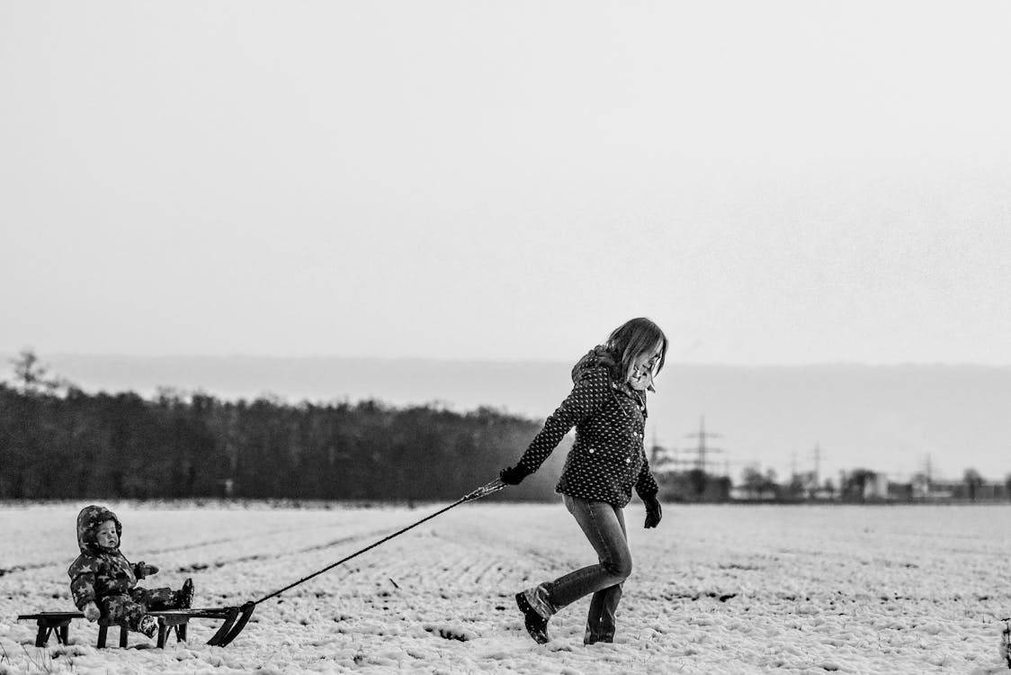 Free Woman Pulling Snow Sled With Baby Stock Photo