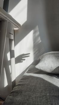 A cozy gray bedroom in Indonesia with playful hand shadows and soft sunlight.