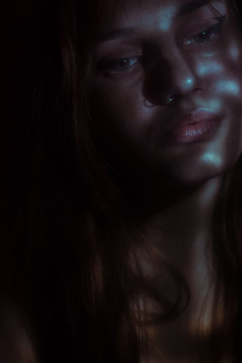 Free Close-up portrait of a woman in low light with dramatic shadows. Stock Photo