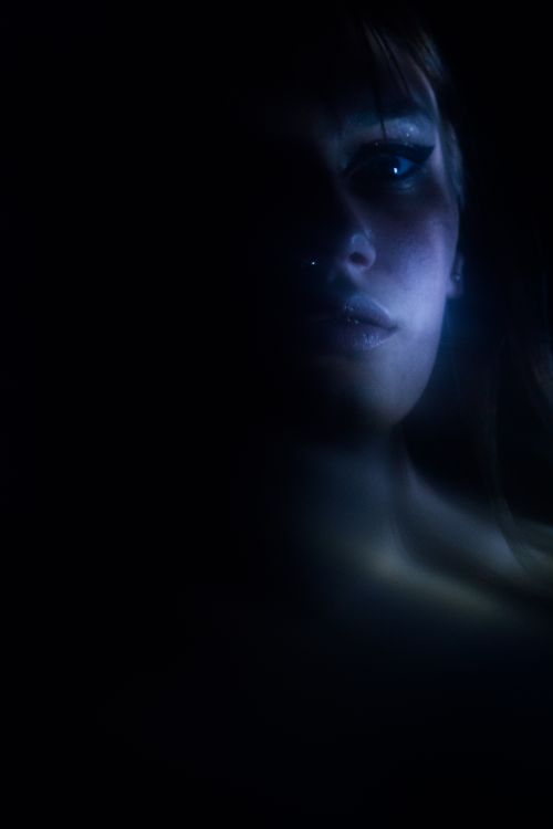 Free A captivating low-light portrait highlighting the mystery of a woman's expression. Stock Photo