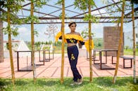 在一个阳光明媚的日子，一位时尚的女人身着充满活力的黄色和蓝色衣服，出现在竹子花园里