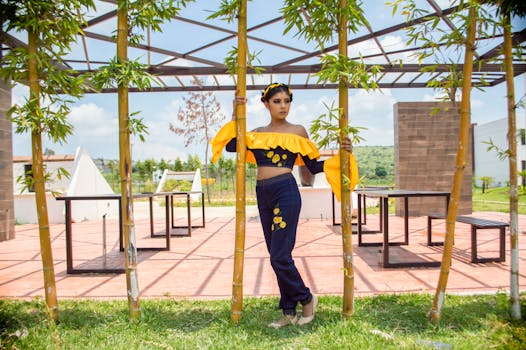 在一个阳光明媚的日子，一位时尚的女人身着充满活力的黄色和蓝色衣服，出现在竹子花园里