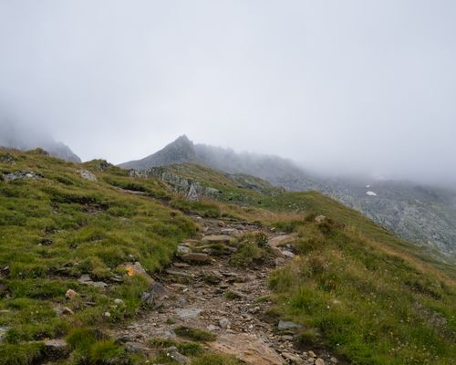 Free A scenic rocky trail amidst foggy mountains and lush greenery, perfect for nature enthusiasts. Stock Photo