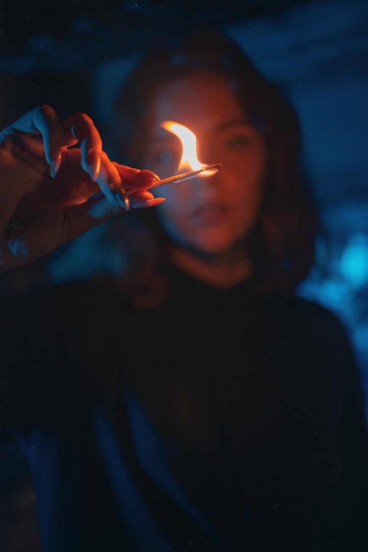 A Woman In Black Shirt Holding A Burning Matchstick