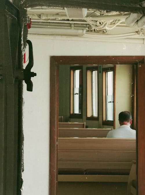 Refection of a Man Sitting on a Wooden Bench from the Mirror