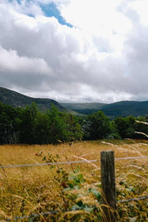 Free Peaceful rural scene featuring mountains, fields, and cloudy sky. Stock Photo