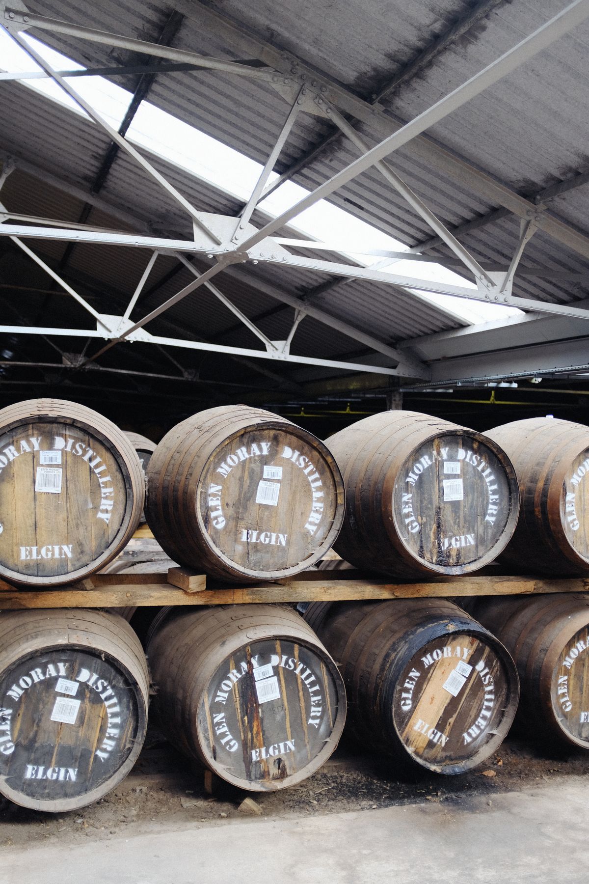Wooden barrels in Glen Moray Distillery warehouse for aging whisky. Illustrative editorial photograph.